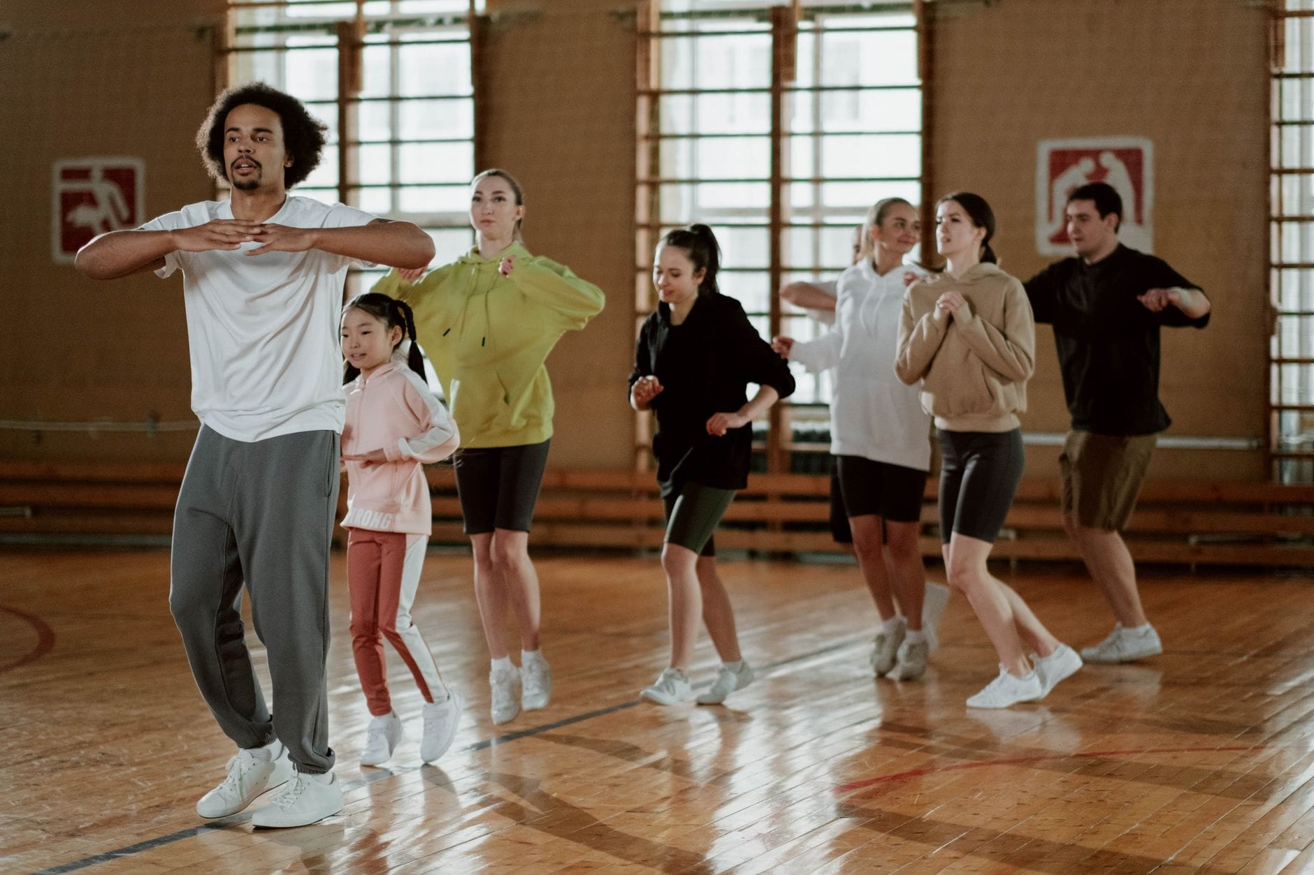 Grupa dorosłych ćwiczy energiczny taniec fitness w sali w Poznaniu