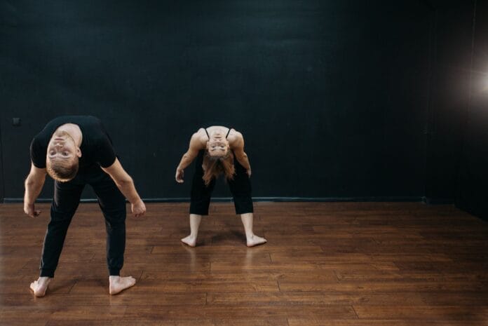 Dwoje tancerzy odchyla się w próbie tańca współczesnego w studio Dwoje tancerzy odchyla się w próbie tańca współczesnego w studio